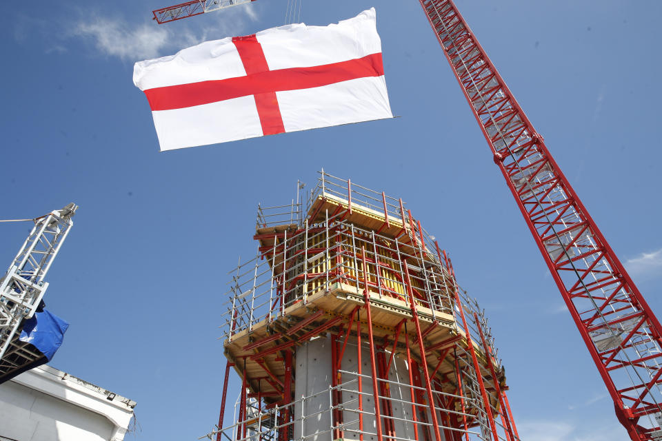 The flag of Genoa flies next to one of the new pillars being built, during a remembrance ceremony to mark the first anniversary of the Morandi bridge collapse, in Genoa, Italy, Wednesday, Aug. 14, 2019. The Morandi bridge was a road viaduct on the A10 motorway in Genoa, that collapsed one year ago killing 43 people. (AP Photo/Antonio Calanni)