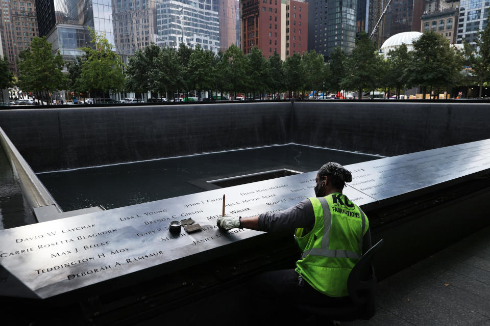 A worker polishes the bronze parapets surrounding the twin memorial pools where the names of the men, women, and children killed in the 9/11 attacks are inscribed in New York on Sept. 8, 2021. (Chip Somodevilla / Getty Images)