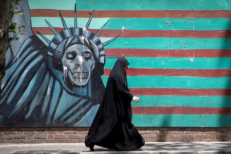 A woman walks in front of a mural depicting the Statue of Liberty in Tehran