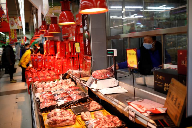 A worker wearing a face mask grabs a piece of meat from the scale at a supermarket, as the country is hit by an outbreak of the new coronavirus, in Beijing