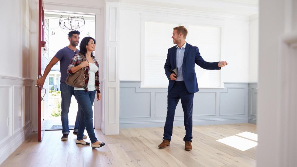 Realtor Showing Hispanic Couple Around New Home.