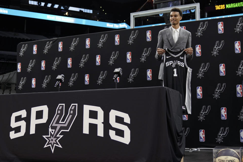 San Antonio Spurs' Victor Wembanyama, the No. 1 draft pick, holds up a jersey during an introductory NBA basketball press conference, Saturday, June 24, 2023, in San Antonio. (AP Photo/Eric Gay)