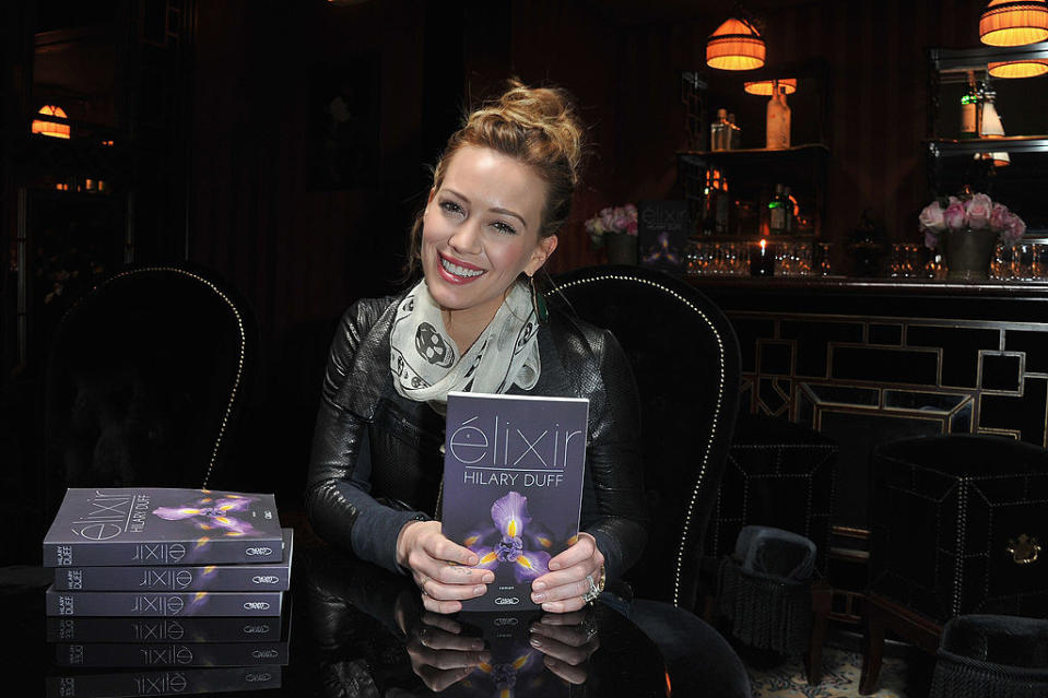 hilary at a book signing holding up her book