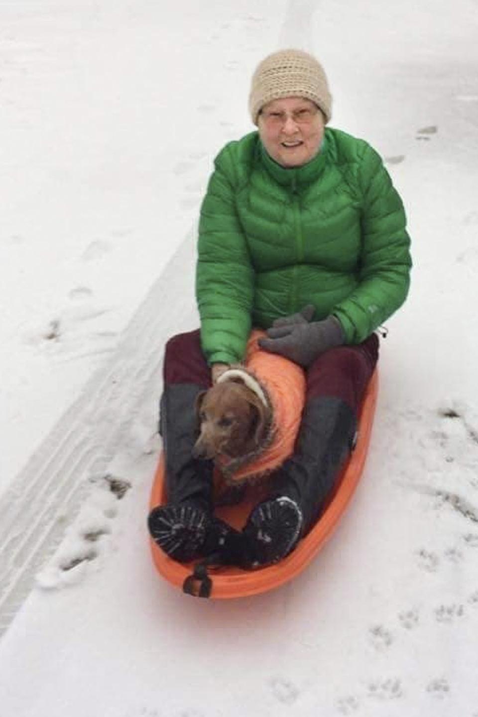 Joanne Mellady y su perrito se deslizan en un trineo después de una nevada en su casa de Washington, New Hampshire, en diciembre del 2016. Mellady sobrevivió a un doble trasplante de pulmón en el 2007, pero falleció por el coronavirus a fines de marzo.(Joyce Smith via AP)