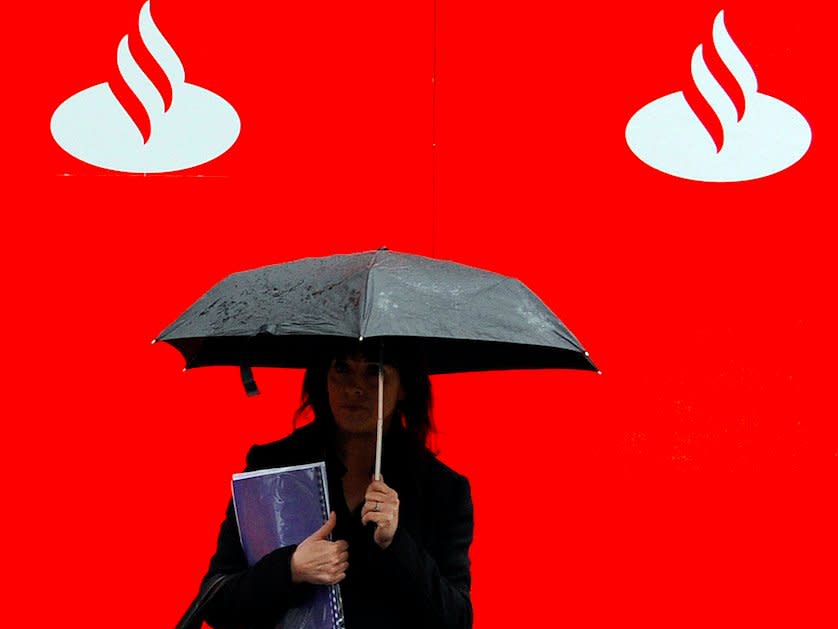 A pedestrian stands beside a logo for Spain's Banco Santander in London January 28, 2009. Spain's Santander will compensate all individual clients who suffered losses in the alleged Bernard Madoff fraud, the bank said on Tuesday.The bank plans to issue 1.38 billion euros ($1.82 billion) in preferential shares with an annual 2 percent coupon to compensate its clients, it said.