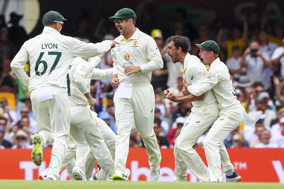 Australia's Mitchell Starc, second right, is congratulated by teammates after taking the wicket of England's Rory Burns during day one of the first Ashes cricket test at the Gabba in Brisbane, Australia, Wednesday, Dec. 8, 2021. (AP Photo/Tertius Pickard)