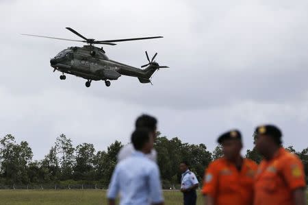 Search and rescue team members stand by as a helicopter prepares to land, during search operations for passengers onboard AirAsia flight QZ8501, at Iskandar airbase in Pangkalan Bun district, Indonesia, December 31, 2014. REUTERS/Beawiharta