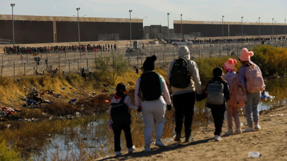 Migrants seeking asylum in the United States stand on the banks of the Rio Grande at the southern US border, as seen from Ciudad Juarez, Mexico, on December 18, 2023. - Jose Luis Gonzalez/Reuters