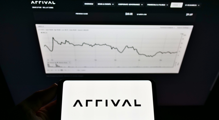 Person holding mobile phone with logo of electric vehicle manufacturer Arrival Ltd. (ARVL) on screen in front of website with chart. Focus on phone display. Unmodified photo.