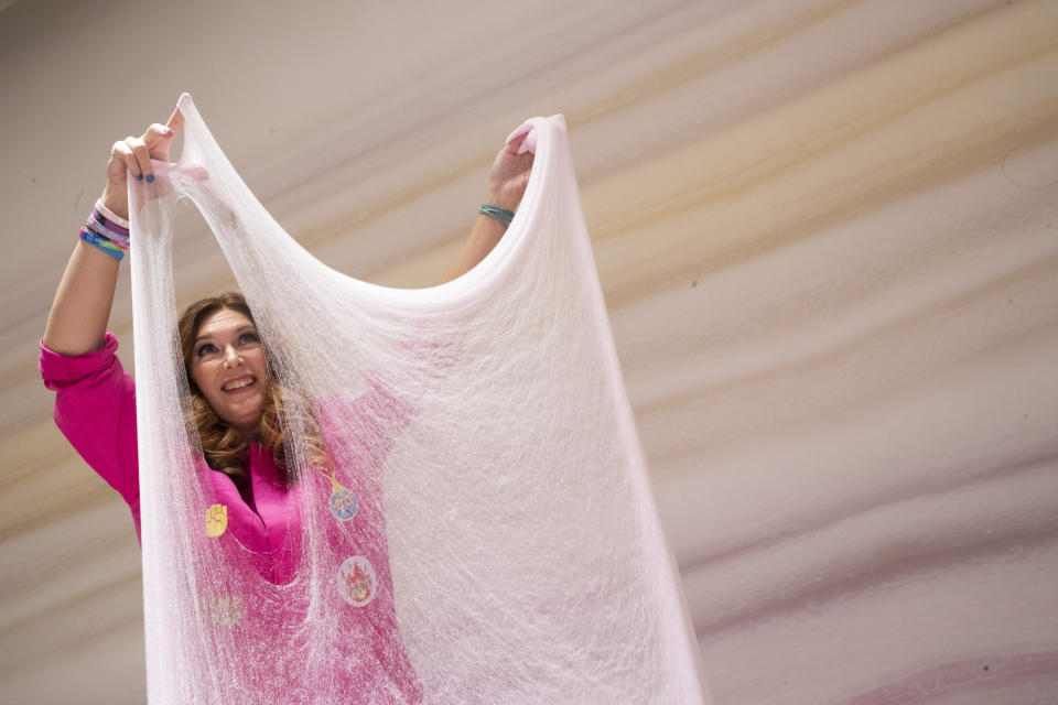 This Oct. 21, 2019, photo shows Sara Schiller stretching cloud slime during a preview of the Sloomoo Institute in New York. An immersive, 8,000-square-foot museum dedicated to all things slime opens Friday for a nearly six-month celebration before hitting the road to other locales. (AP Photo/Mary Altaffer)