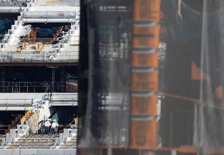 Men work at the construction site of the New National Stadium, main stadium of Tokyo 2020 Olympics and Paralympics, in Tokyo, Japan December 22, 2017. REUTERS/Issei Kato