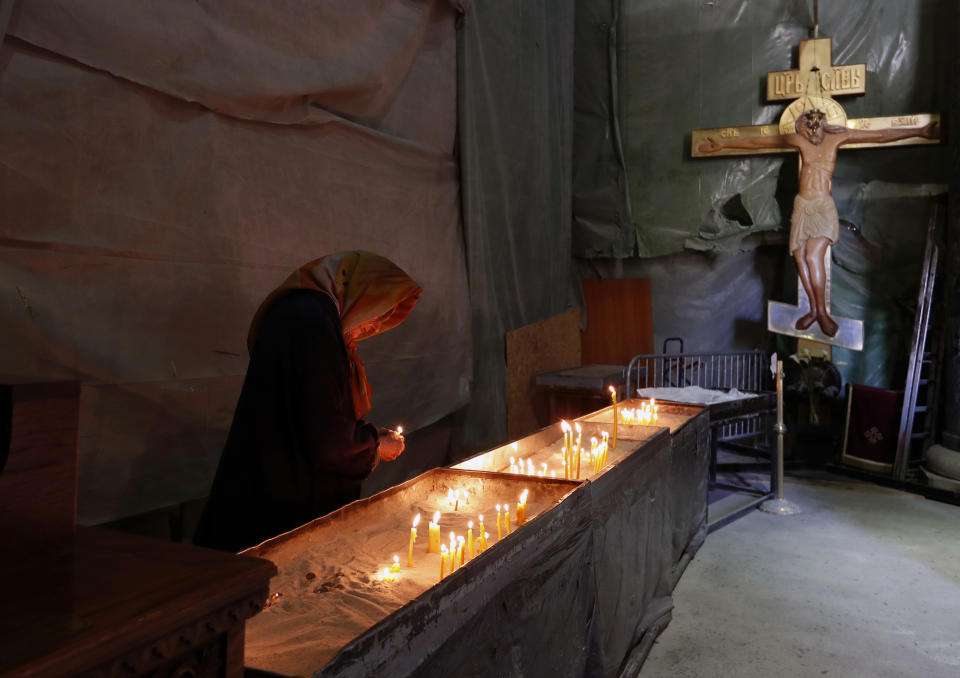In this Thursday, April 16, 2020, photo a woman lights a candle inside the St. Sava Temple in Belgrade, Serbia. For Orthodox Christians, this is normally a time of reflection, communal mourning and joyful release, of centuries-old ceremonies steeped in symbolism and tradition. But this year, Easter - by far the most significant religious holiday for the world's roughly 300 million Orthodox - has essentially been cancelled. (AP Photo/Darko Vojinovic)
