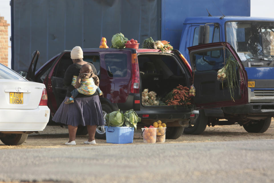 People sell various goods by the side of a busy road in Harare, Zimbabwe, Tuesday, June, 23, 2020. Cars have become mobile markets in Zimbabwe where enterprising residents are selling goods from their vehicles to cope with economic hardships caused by the coronavirus. With their car doors and trunks wide open by the side of busy roads, eager sellers display a colorful array of goods in Harare, the capital. (AP Photo/Tsvangirayi Mukwazhi)