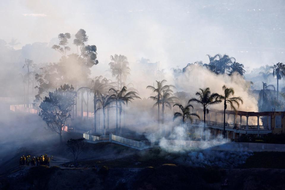 expensive home with palm trees burns in wildfire