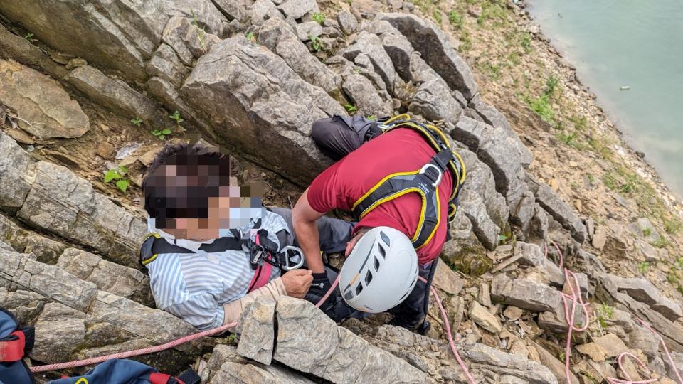 消防人員利用繩索攀爬至石壁上，才將男子垂降至岸邊。圖：讀者提供