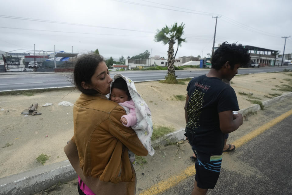 A family crosses near an avenue flooded by the rains of Hurricane Norma in San Jose del Cabo, Mexico, Saturday, Oct. 21, 2023. Norma had weakened and was downgraded to Category 1 on the hurricane wind scale. It was located 25 miles west of Cabo San Lucas storm with winds of 85 mph (140 kmh) and expected to make landfall on Saturday, according to the U.S. (AP Photo/Fernando Llano)