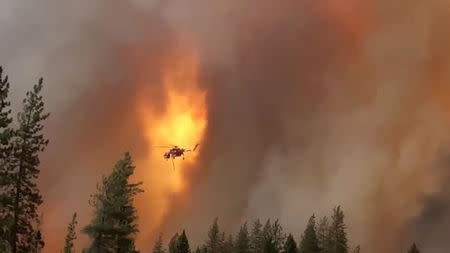 A helicopter drops water on a forest fire in Shasta County in California, U.S., September 5, 2018 in this picture obtained on September 6, 2018 from a social media video. CALIFORNIA HIGHWAY PATROL/via REUTERS