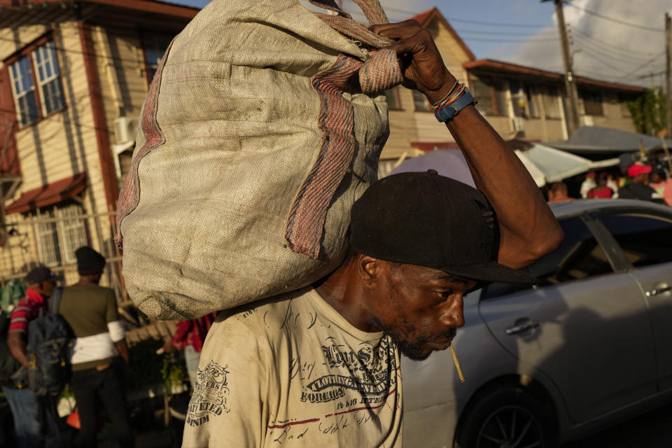 A market worker carries a sack of fruits at Stabroek Market in Georgetown, Guyana, Thursday, April 13, 2023. More than 40% of the population lived on less than $5.50 a day when oil production began in 2019. (AP Photo/Matias Delacroix)