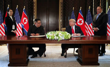 U.S. President Donald Trump and North Korea's leader Kim Jong Un look at each others before signing documents that acknowledge the progress of the talks and pledge to keep momentum going, after their summit at the Capella Hotel on Sentosa island in Singapore June 12, 2018. They are flanked by Kim Yo Jong, sister of North Korean leader Kim Jong Un, and U.S. Secretary of State Mike Pompeo. REUTERS/Jonathan Ernst