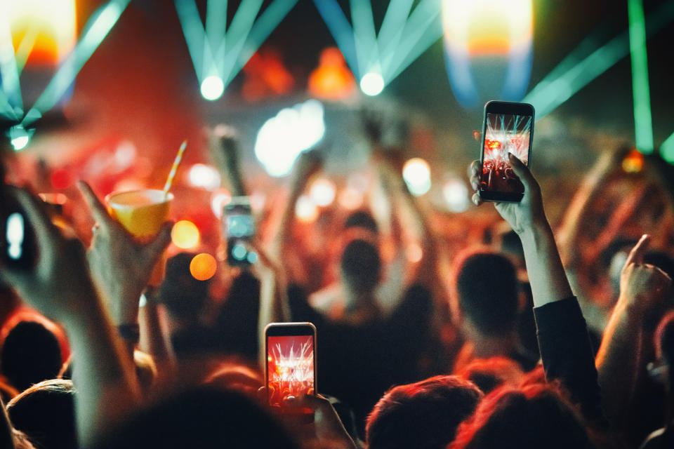 People holding up their phones and filming at a concert