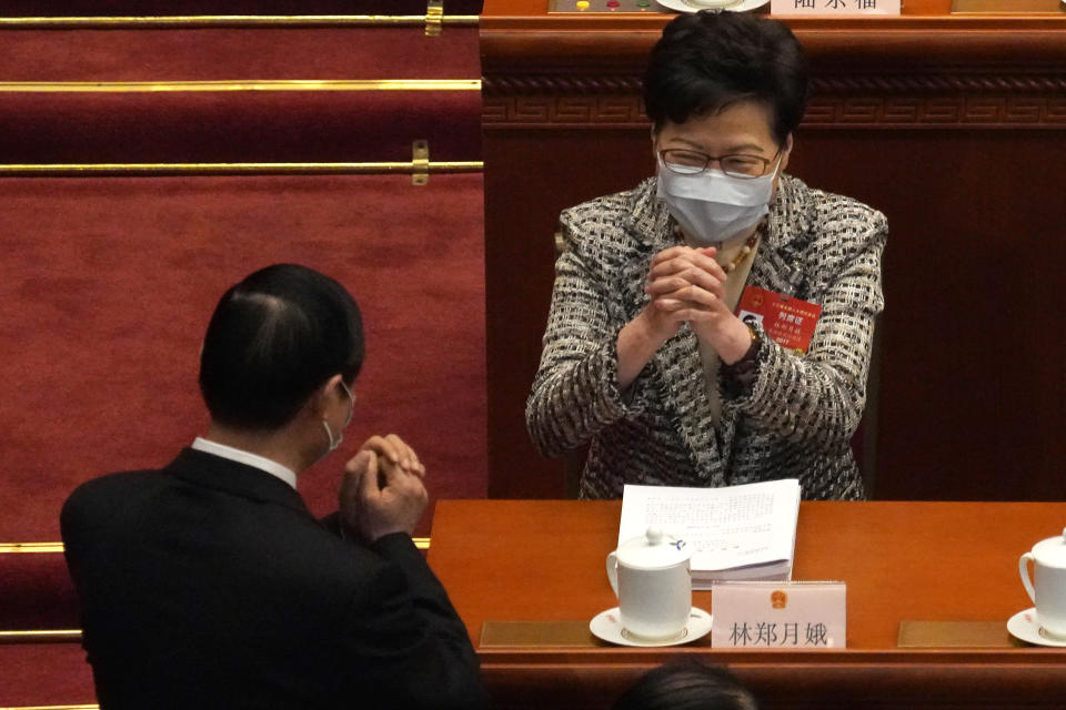 Hong Kong Chief Executive Carrie Lam, right, exchanges greetings with a fellow delegate before the opening session of China's National People's Congress (NPC) at the Great Hall of the People in Beijing, Friday, March 5, 2021. (AP Photo/Andy Wong)