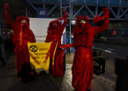 Demonstrators hold a banner reading "standing by and watching is no longer an option" outside the court building prior to the start of the court case of Milieudefensie, the Dutch arm of the Friends of the Earth environmental organization, against Shell in The Hague, Netherlands, Tuesday, Dec. 1, 2020. A landmark legal battle opened as climate change activists in the Netherlands go to court seeking an order for energy giant Shell to rein in its carbon emissions. (AP Photo/Peter Dejong)