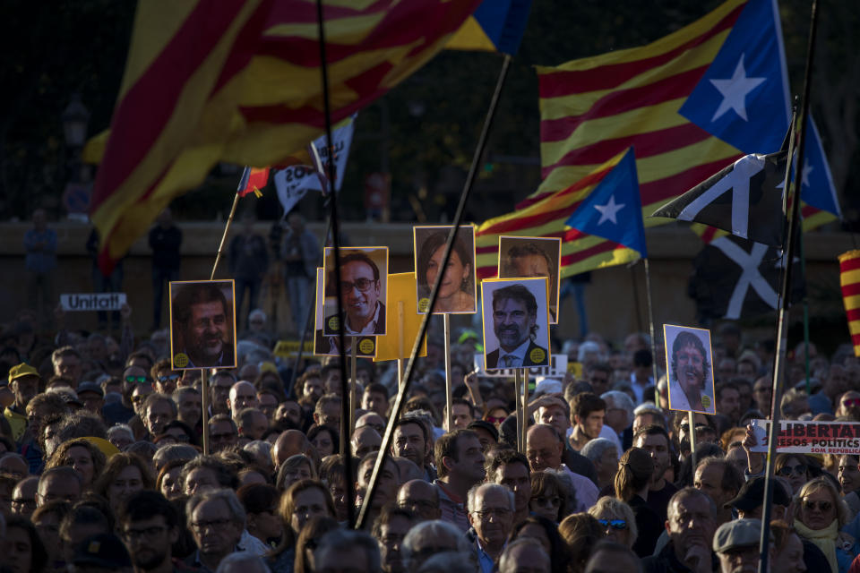 People hold independence flags and portraits of Catalan separatist leaders and activists jailed during a demonstration in downtown Barcelona, Spain, Wednesday, June 12, 2019. Catalan separatist leaders and activists told their Supreme Court trial on Wednesday they were exercising their democratic rights when they held a banned referendum on breaking away from Spain, denying charges of rebellion and sedition. (AP Photo/Emilio Morenatti)