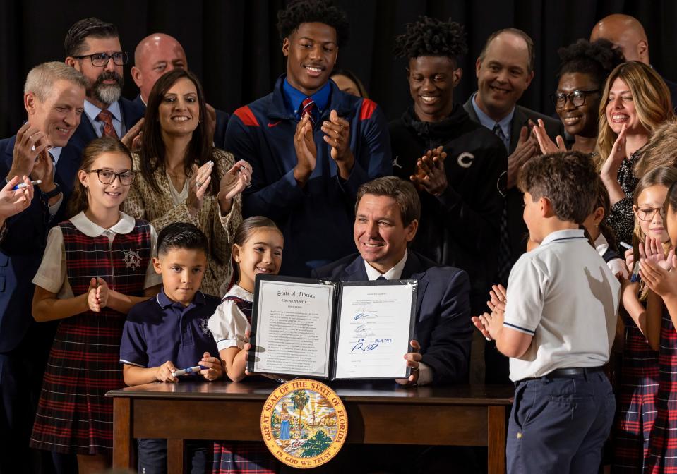 Florida Gov. Ron DeSantis signs a bill to expand school vouchers statewide on March 27, 2023, in Miami.