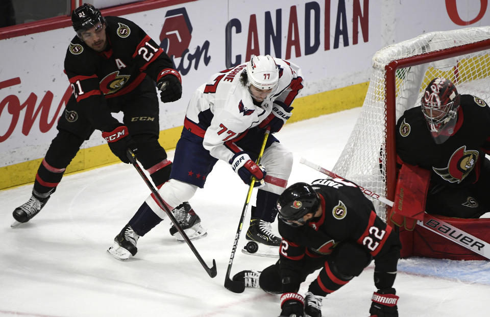 Ottawa Senators defenseman Nikita Zaitsev (22) and left wing Nick Paul (21) try to prevent Washington Capitals right wing T.J. Oshie (77) from scoring on goaltender Filip Gustavsson (32) during the second period of an NHL hockey game in Ottawa, Ontario, on Monday, Oct. 25, 2021. Oshie scored on the play for a hat-trick. (Justin Tang/The Canadian Press via AP)