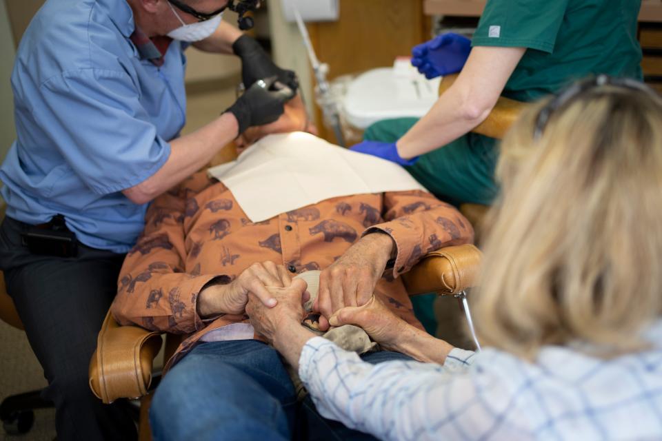 After telling him that the dentist appointment was her own just to get him to the office, Suzi Hanna holds the hands of her husband, Jack, as Dr. Michael Bowman repairs a crown and cavity in Jack’s mouth.