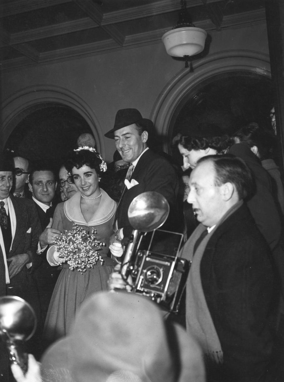 <p>Elizabeth Taylor's second wedding was less grand than her first. Wearing a simple belted dress and flowers in her chignon, Elizabeth and Michael Wilding got married at Caxton Hall in London. </p>