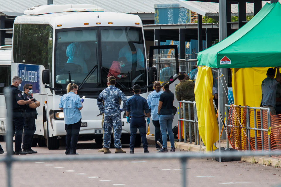 Multiple government agencies gather beside buses to take Australian evacuees from the coronavirus-struck cruise ship Diamond Princess after they arrived on a Qantas flight from Japan at Darwin International Airport in Darwin.