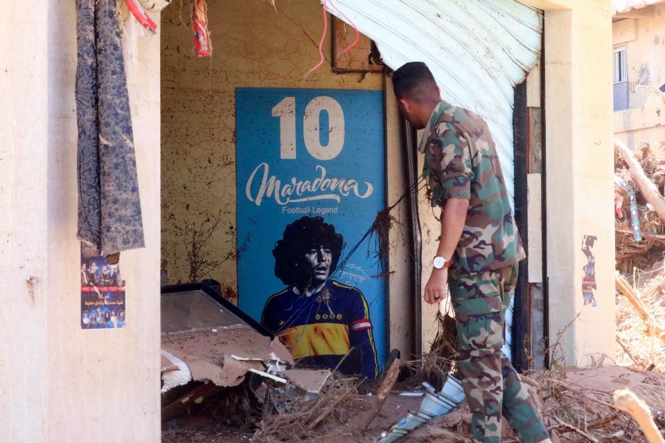 A soldier stares at a poster of late Argentinian football star Diego Maradona standing amid the ruins of a house destroyed in flash floods in Libya's eastern city of Derna, on September 14, 2023. (Abdullah DOMA/AFP via Getty Images)