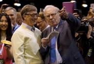 FILE PHOTO: Berkshire Hathaway CEO Warren Buffett shows his friend Microsoft co-founder Bill Gates the finer points of newspaper tossing, prior to the Berkshire annual meeting in Omaha