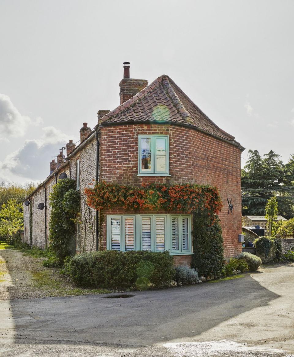 a brick cottage with green window frames