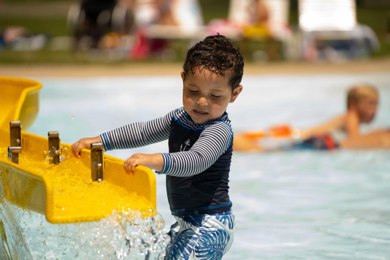 Aziel Lopez, 2, lays in the splash pad to beat the heat on Tuesday, June 14, 2022 at Kennedy Park in South Bend.