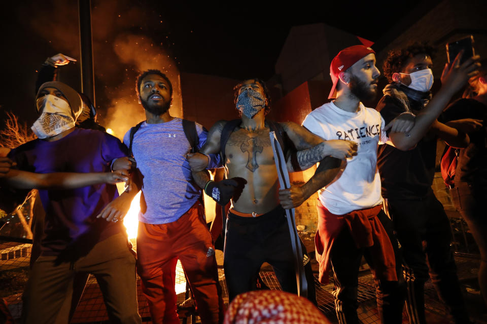 Protestors demonstrate outside of a burning Minneapolis 3rd Police Precinct, Thursday, May 28, 2020, in Minneapolis. Protests over the death of George Floyd, a black man who died in police custody Monday, broke out in Minneapolis for a third straight night. (AP Photo/John Minchillo)