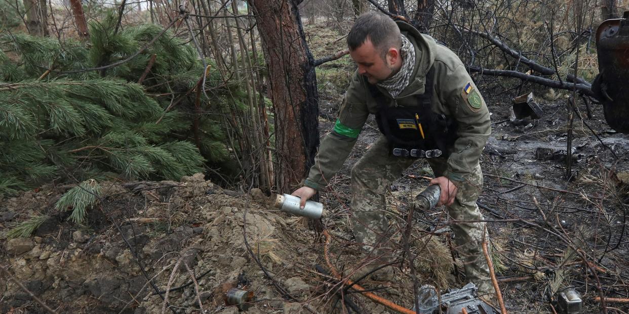 A Ukrainian military office picks up a cluster bomb left after Russia's invasion near the village of Motyzhyn, in Kyiv region, Ukraine April 10, 2022. REUTERS/Mykola Tymchenko