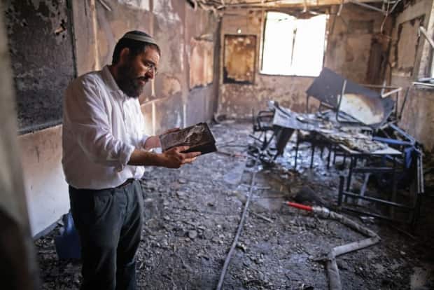 A rabbi inspects the damage inside a torched religious school in the central Israeli city of Lod last Tuesday following a night of violent confrontation between Arab and Jewish Israelis. Riots in several Israeli cities have left behind a trail of damaged schools, synagogues, cars and homes and instilled fear in residents.