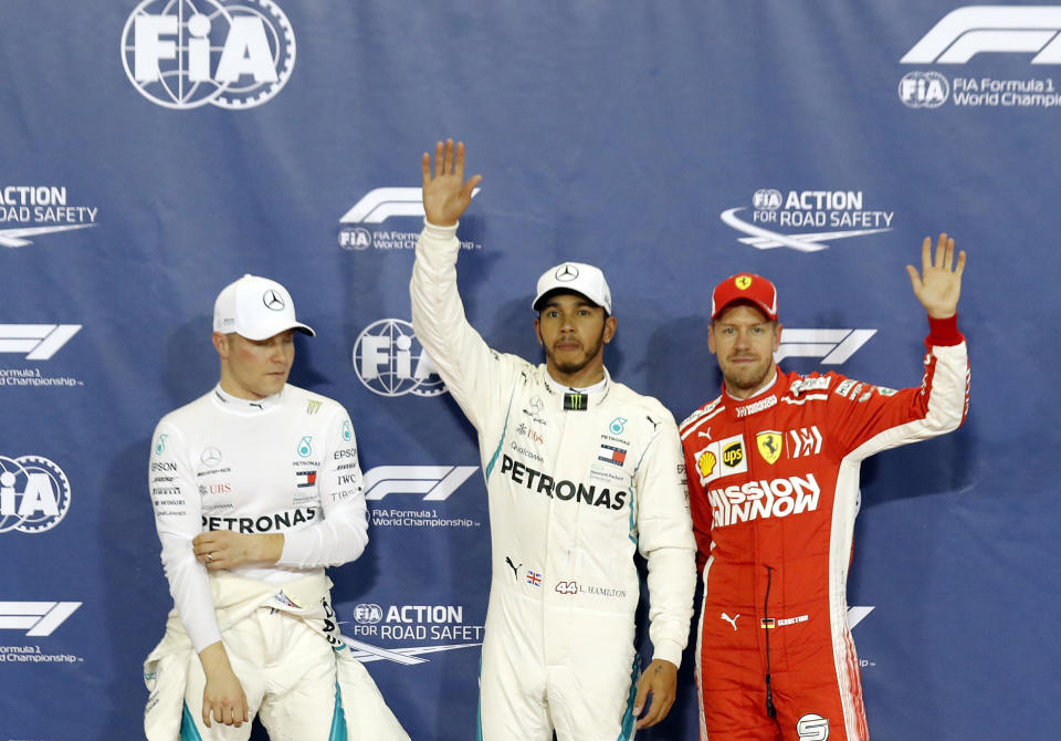 Mercedes driver Lewis Hamilton of Britain, center, who earned pole position, Ferrari driver Sebastian Vettel of Germany, right, who came in third and Mercedes driver Valtteri Bottas of Finland, left, who earned the second best time, posing for photos after the qualifying session for the Emirates Formula One Grand Prix at the Yas Marina racetrack in Abu Dhabi, United Arab Emirates, Saturday, Nov. 24, 2018. The Emirates Formula One Grand Prix will take place on Sunday. (AP Photo/Hassan Ammar)