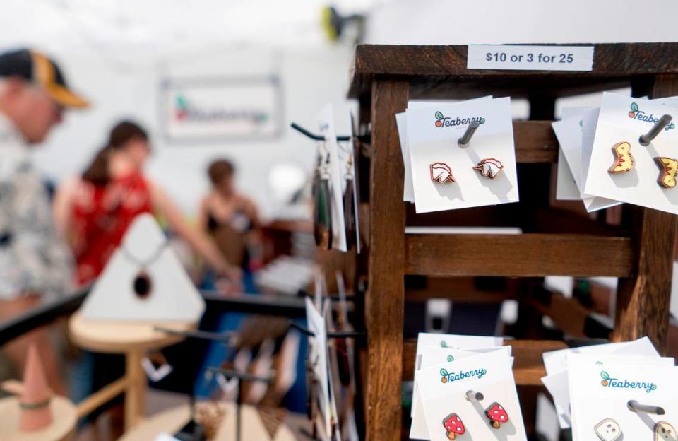 Guests browse the wooden earrings and pins hand painted by Amanda Jones in her Teaberry Design Co. booth at the People’s Choice Festival on Friday, July 14, 2023.