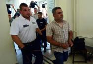 One of four suspects in the Austrian motorway migrant tragedy are led by a Hungarian police official (centre) into the Kecskemet courtroom in Kecskemet, Hungary on August 29, 2015