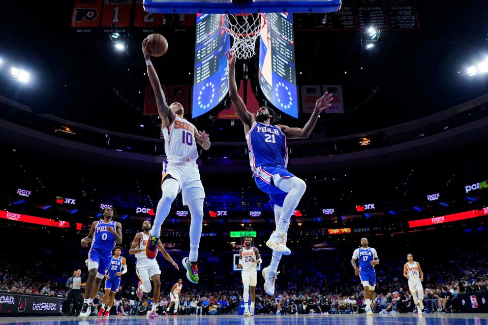 Phoenix Suns' Damion Lee, left, goes up for a shot against Philadelphia 76ers' Joel Embiid during the first half of an NBA basketball game, Monday, Nov. 7, 2022, in Philadelphia. (AP Photo/Matt Slocum)