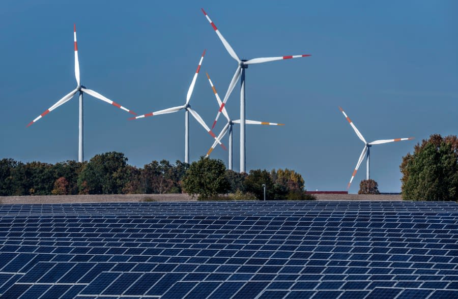 FILE - Wind turbines turn behind a solar farm in Rapshagen, Germany, Oct. 28, 2021. Germany has called for governments around the world to work on setting an ambitious target for renewable energy that would "ring in the end of the fossil fuel age" and help prevent dangerous global warming. Germany welcomed a deal Friday, June 16, 2023 among European Union countries to increase by more than a third the bloc’s renewable energy target for 2030. (AP Photo/Michael Sohn, File)