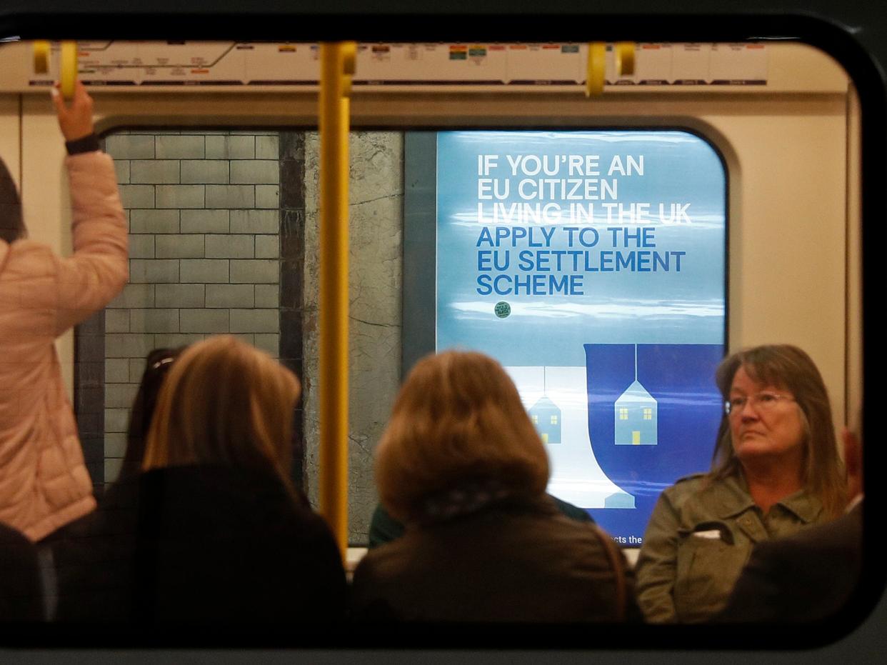 <p>A poster, aimed at EU citizens living in the UK, encourages EU nationals to apply to the Government's post-Brexit EU settlement scheme, is pictured through a carriage of a London Underground tube train, at St James's Park underground station in London</p> (AFP/Getty)