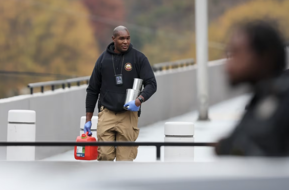 An Atlanta Fire & Rescue official removes a gasoline can from the scene after a protester set themself on fire outside the Israeli consulate on Dec. 1, 2023. (Jason Getz/Atlanta Journal-Constitution/The Associated Press)