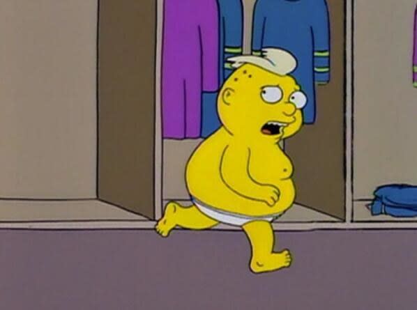 A fat boy with blonde hair runs through a change room in his underwear, looking scared