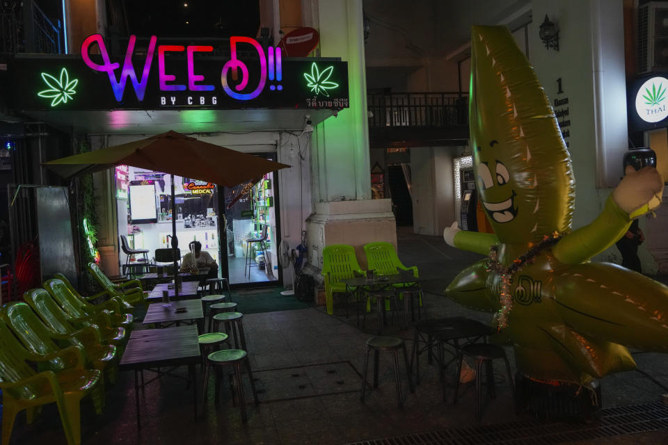 A tourist sits outside a cannabis shop in Bangkok, Thailand, Wednesday, May 15, 2024. Dozens of pro-cannabis advocates in Thailand gathered at the health ministry on Thursday to oppose the government’s plan to relist the plant as a narcotic, two years after it was decriminalized. (AP Photo/Sakchai Lalit)