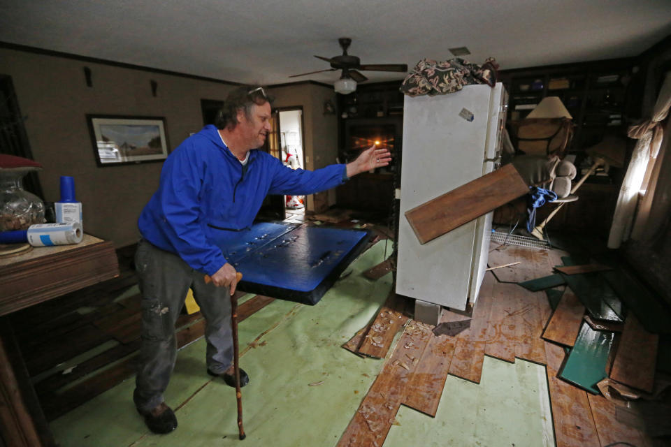 Jeff Sharp tosses floodwater-damaged flooring into a pile as he helps his brother clean up following flooding from the Pearl River in northeast Jackson, Miss., Wednesday, Feb. 19, 2020. Depending on how much the water has receded, authorities in various flooded communities, allowed residents to return to their homes. (AP Photo/Rogelio V. Solis)