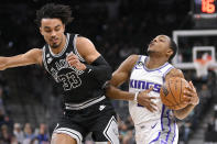 Sacramento Kings' De'Aaron Fox, right, drives against San Antonio Spurs' Tre Jones during the first half of an NBA basketball game, Wednesday, Feb. 1, 2023, in San Antonio. (AP Photo/Darren Abate)